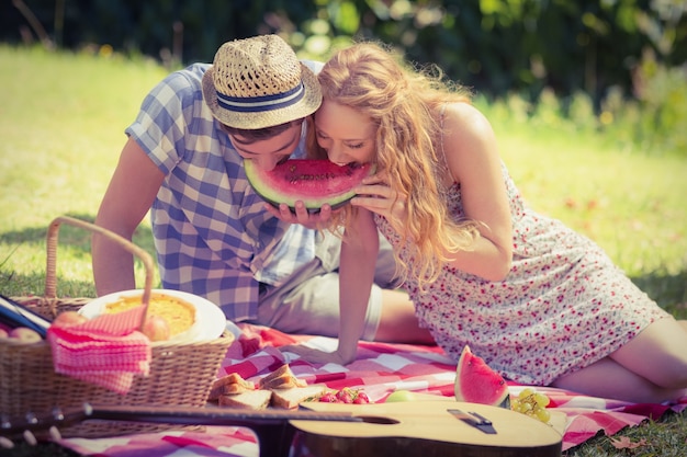 Молодая пара на пикнике едят арбуз