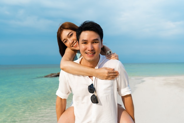 Young couple piggyback ride on the sea beach at Koh MunNork Island, Rayong, Thailand