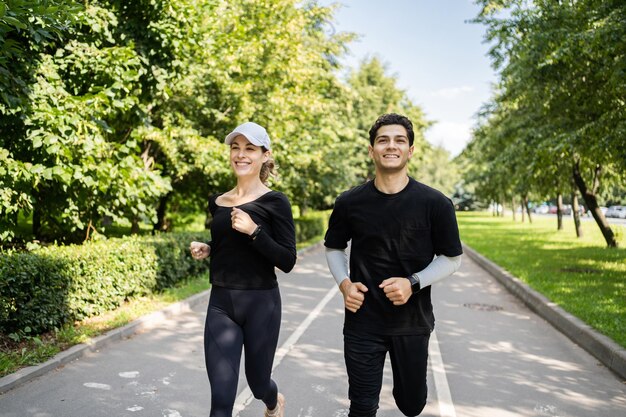 A young couple play sports together Man and woman training running in the park Use a fitness watch