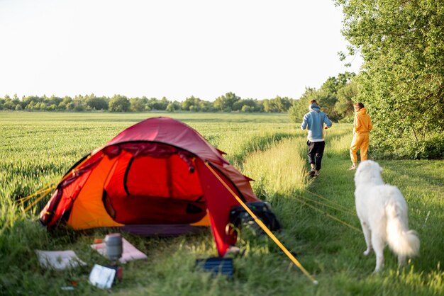 Young couple play with their dog at campsite