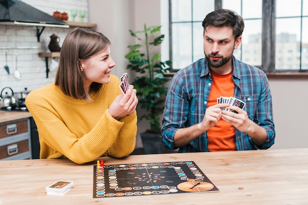 Photo young couple playing the board game in the kitchen