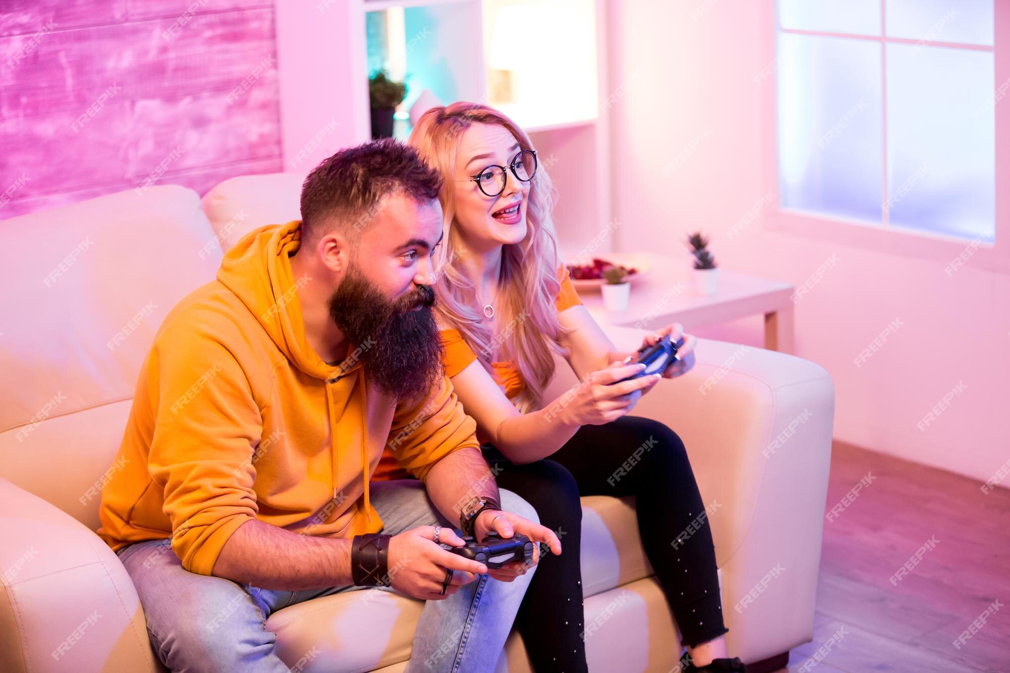 Premium Photo  Boyfriend cheering her beautiul girlfriend while she's playing  online games using wireless controller. room with neon light.