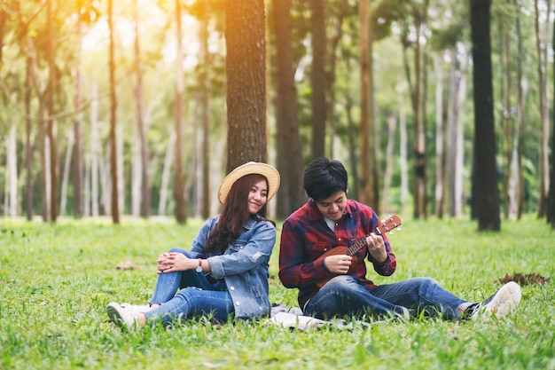 A young couple playing ukulele together in the woods