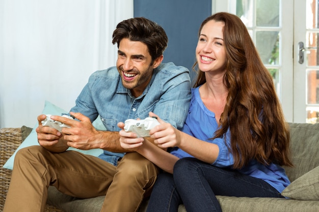 Young couple playing video game while sitting on sofa