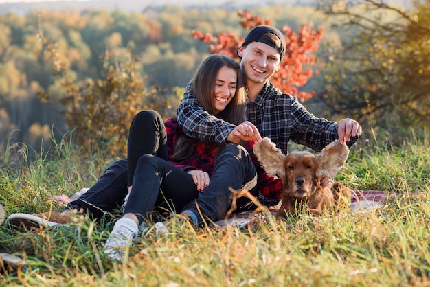 Photo young couple playing with their pet dog on picnic at park