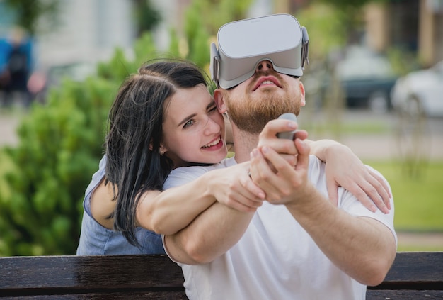 A young couple plays a game using virtual reality glasses on the street.