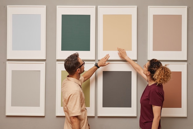 Photo young couple pointing at picture hanging on the wall while they visiting art gallery