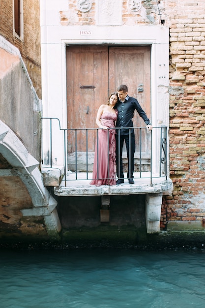 Young couple posing near wooden gate in Venice.