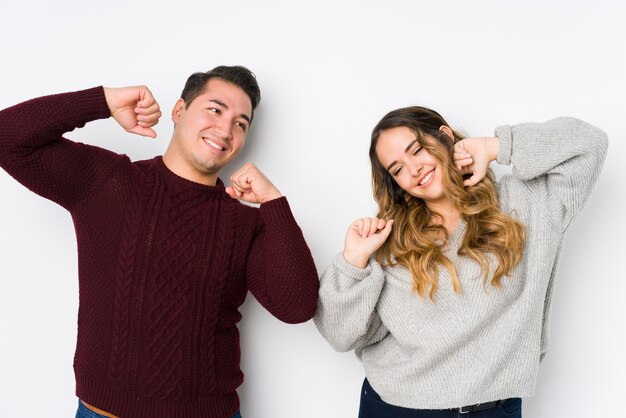 Young couple posing in a white wall stretching arms, relaxed position.