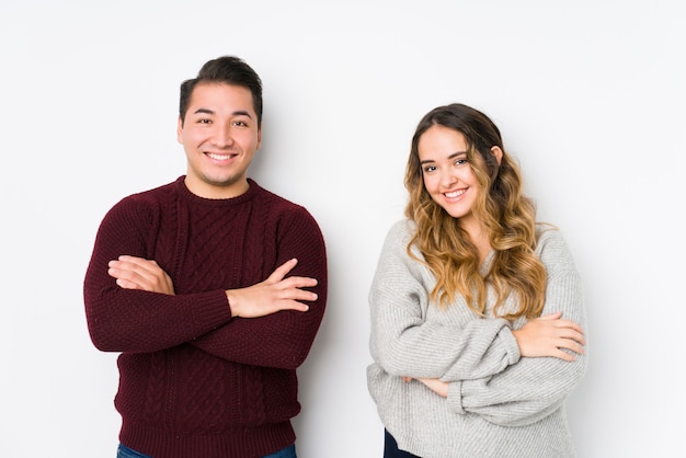 Young couple posing in a white wall who feels confident, crossing arms with determination.