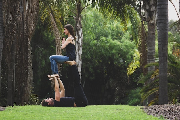 Young couple practicing acro yoga in natural environment Man holding womans feet