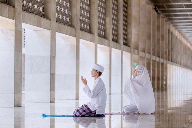 Young couple prays to the Allah after doing Salat