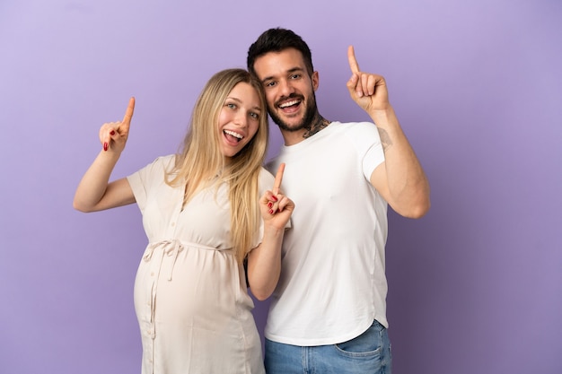 Young couple pregnant and pointing up