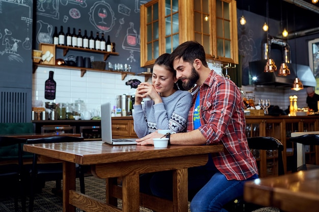 Young couple reading looking at a laptop in cafe