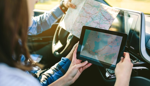 Photo young couple reading map on digital tablet in car