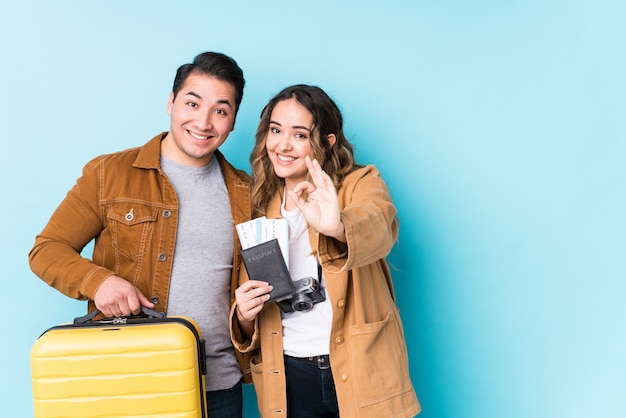 Young couple ready for a travel cheerful and confident showing ok gesture