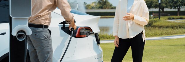 Young couple recharge EV car battery at charging station Expedient