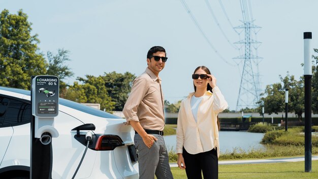 Young couple recharge EV car battery at charging station Expedient