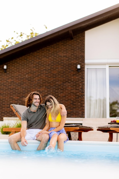 Young couple relaxing by the swimming pool in the house backyard