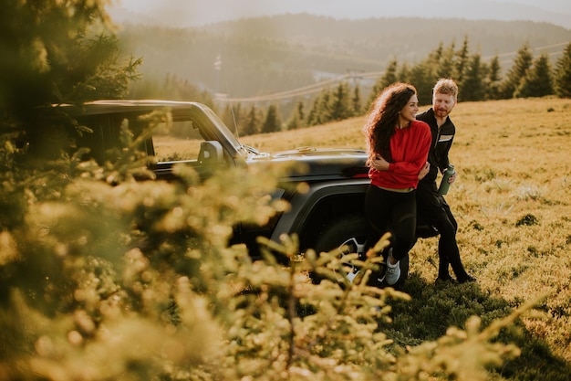 Young couple relaxing by a terrain vehicle hood at countryside