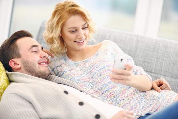 young couple relaxing at home and using smart phone