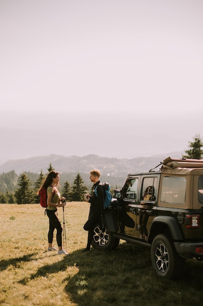 Young couple relaxing on a terrain vehicle hood at countryside