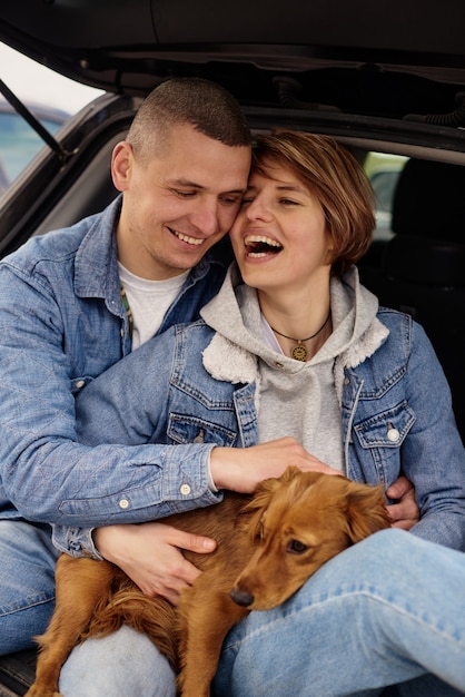 犬と一緒に車の中で休んでいる若いカップル。