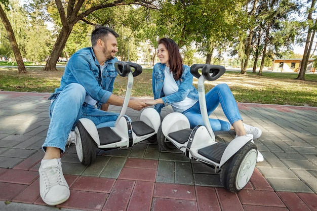 A young couple riding a hoverboard in a park