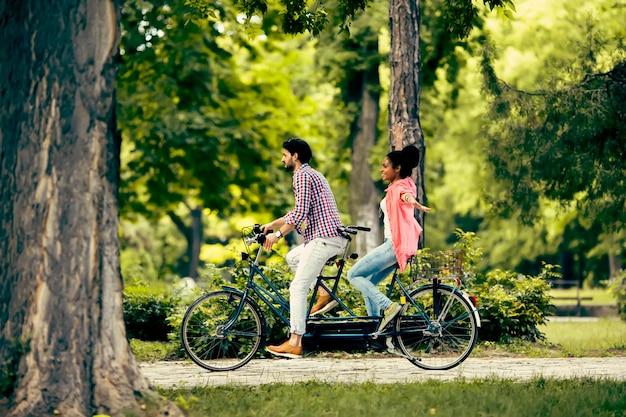 Young couple riding on the tandem bicycle