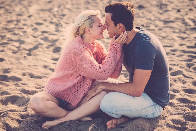 Young couple romancing while sitting on sand at beach