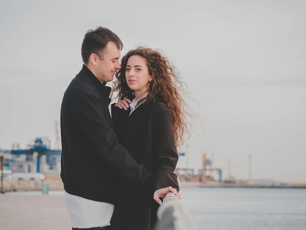 young couple romancing while standing by sea against sky