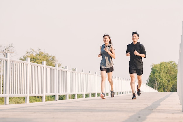 Young couple runner running on running road in city park