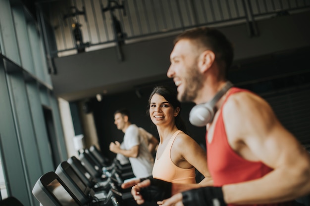 Young couple running on treadmills in modern gym