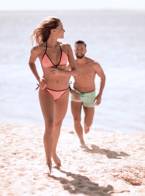 Photo young couple running on a tropical beach at sunset