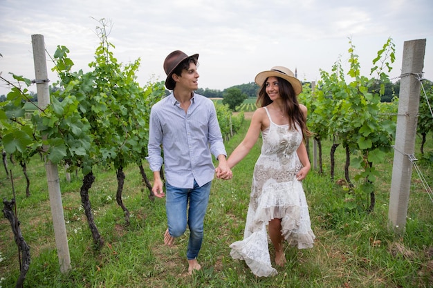 Young couple runs romantically barefoot through the vineyard looking into each other39s eyes