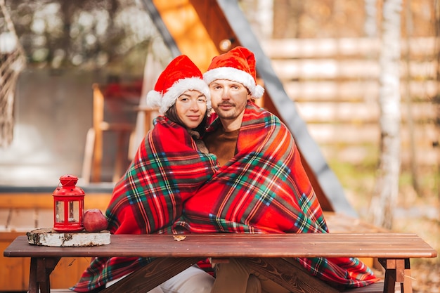 Young couple in Santa hat sitting outdoors during autumn