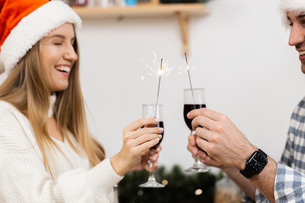 Young couple in Santa hats drinking wine and celebrating Christmas, close up