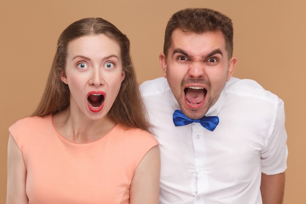 Young couple screaming and looking at camera with shocked face