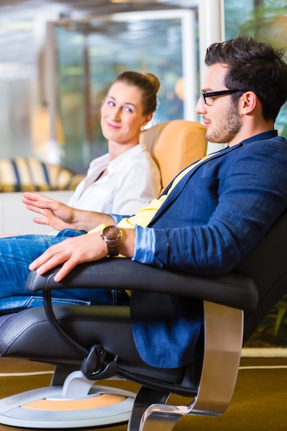 Young couple selecting together armchair in furniture store