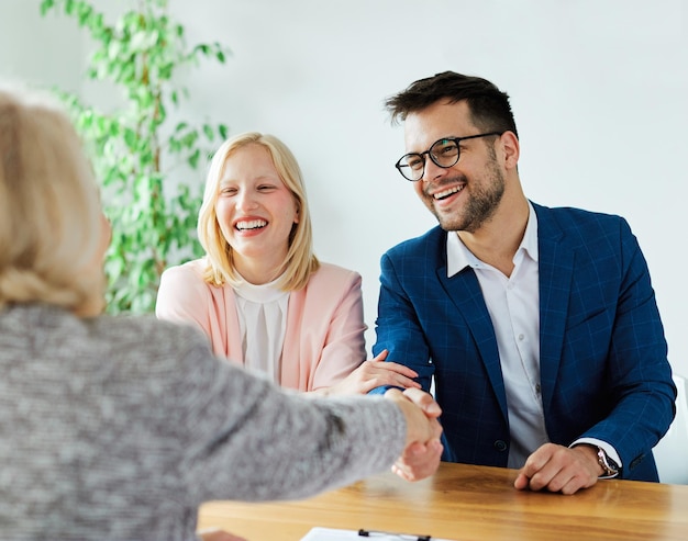 Young couple shaking hands deal contract real estate ihandshake signing