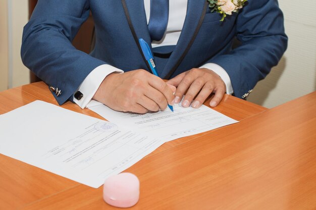 결혼식 문서에 서명 하는 젊은 부부 손에 초점