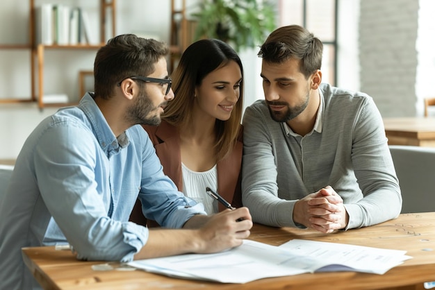 A young couple sits at a table discussing insurance options with a financial advisor showcasing plan