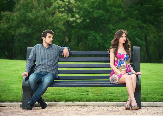 Young couple sitting apart on the bench in the park