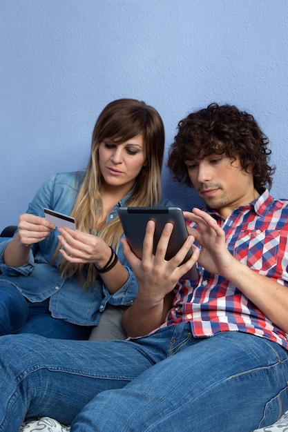 Photo young couple sitting on the bed making an online purchase with the tablet