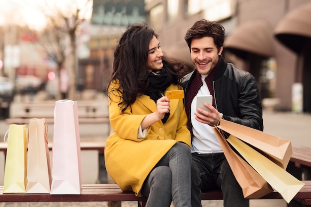 Young couple sitting on bench after shopping