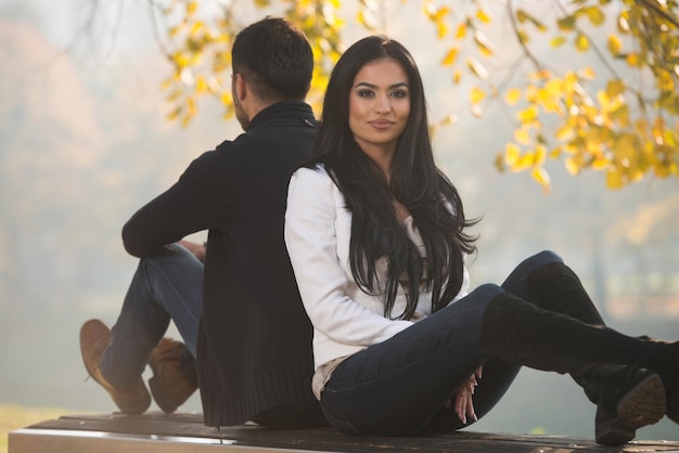 Young Couple Sitting On A Bench In The Beautiful Autumn Day