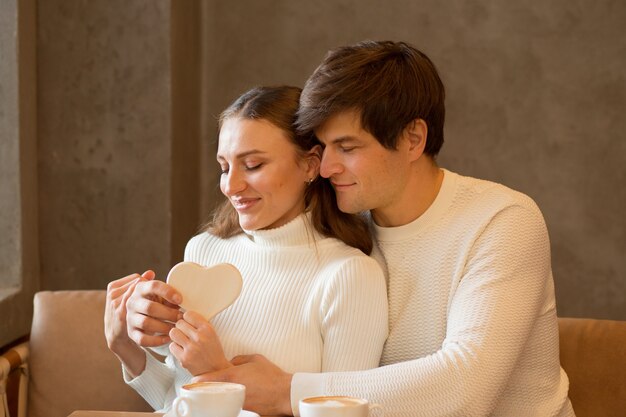 コーヒーと木の心とカフェに座っている若いカップル。バレンタインデー。