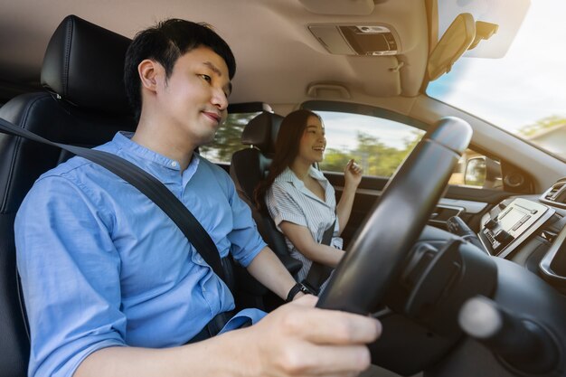 座って車で運転している若いカップル