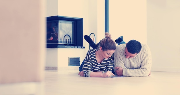 Молодая пара сидит на полу и использует интерент на цифровом планшете