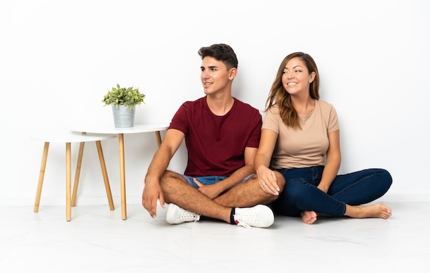 Photo young couple sitting on the floor on white looking side